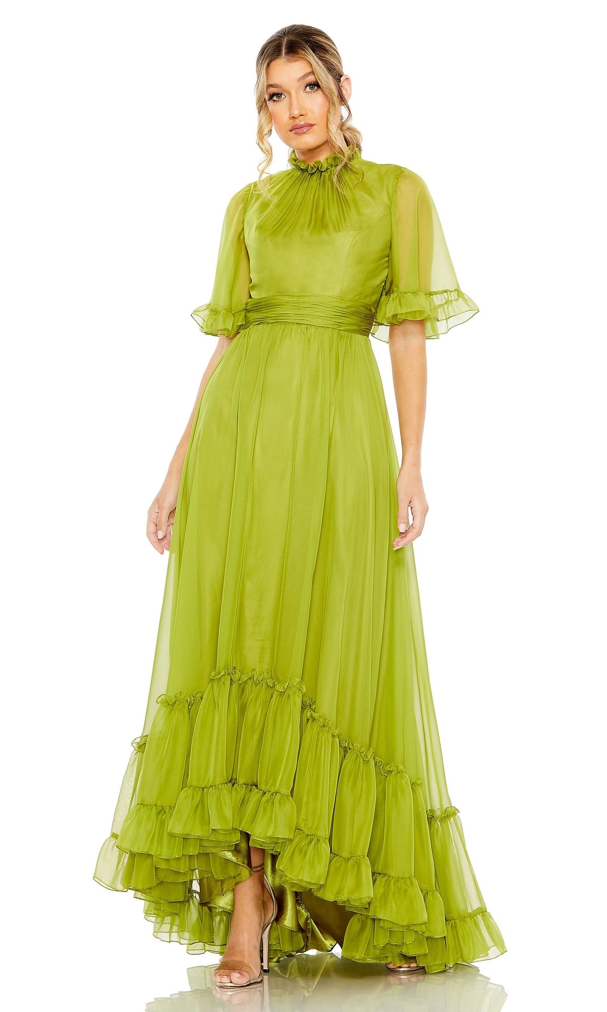 A woman in the Mac Duggal 68229 Short Sleeve Long Formal Dress, a floor-length light green A-line gown with sheer short sleeves and a high neckline, stands against a white background.
